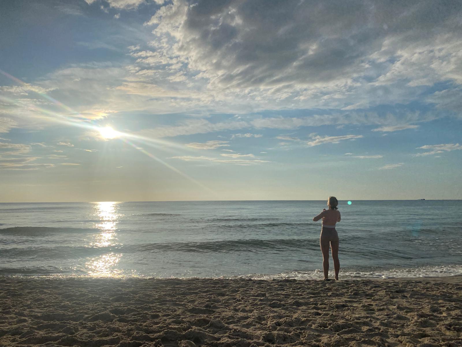 A woman exercising by the sea in Sardinia at sunset